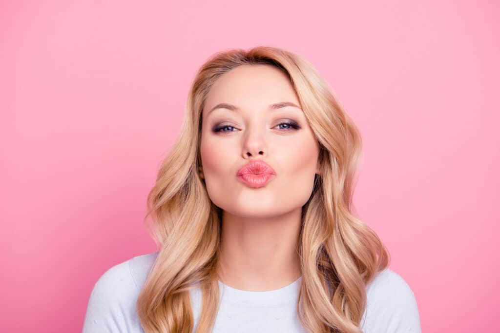 Beautiful woman making a kissy face with full pink lips